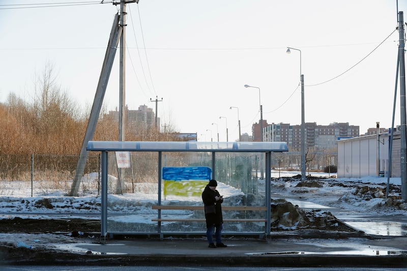 A man waits at a bus stop in St Petersburg, which has been with a painted in the colours of Ukraine's national flag. EPA