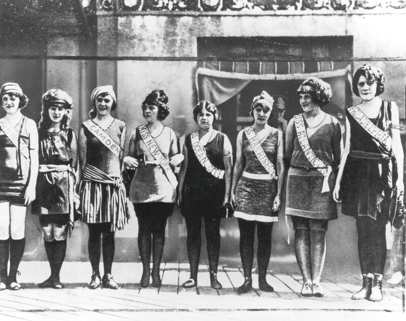 1921:  Full-length portrait of the first Miss America contestants, wearing their sashes over swimsuits, standing in a line on the boardwalk in Atlantic City, New Jersey. Margaret Gorman (second from left), Miss Washington, D.C., was the winner.  (Photo by Hulton Archive/Getty Images)