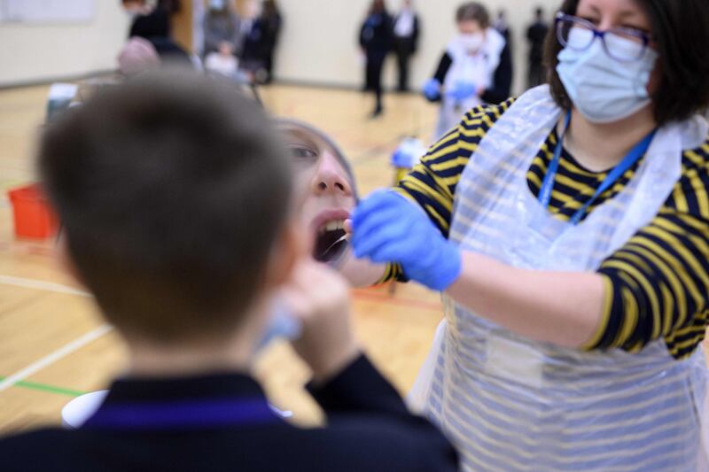 A member of staff at Park Lane Academy in Halifax, England, assists a student as he takes a Covid-19 lateral flow test. AFP