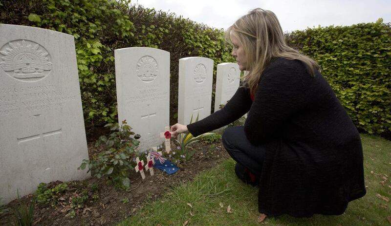 Kaylene Biggs, great-granddaughter of World War I Australian soldier Andrew Bayne, places a wooden cross with a poppy and a message on the grave at Westhof Farm Commonwealth Cemetery in Nieuwkerke, Belgium on Thursday, April 24, 2014. Bayne's grave lies among the 131 Commonwealth soldiers and a handful of German soldiers in this small cemetery surrounded by a landscape still scarred by countless bomb craters, rusting gas shells, bunkers and trenches. Virginia Mayo/AP Photo