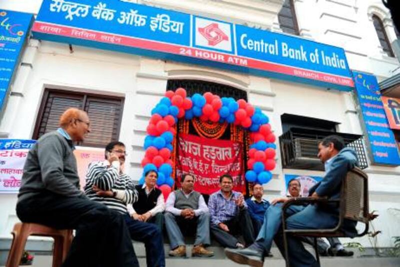 Indian Central Bank employees sit outside a bank during a two day strike called by  trade unions opposing the current UPA governmentís economic policies in Allahabad, on February 20, 2013. Millions of India's workers walked off their jobs in a two-day nationwide strike called by trade unions to protest at the "anti-labour" policies of the embattled government.  Financial services and transport were hit by the strike called by 11 major workers' groups to protest at a series of pro-market economic reforms announced by the government last year, as well as high inflation and rising fuel prices. AFP PHOTO/ SANJAY KANOJIA
 *** Local Caption ***  526056-01-08.jpg