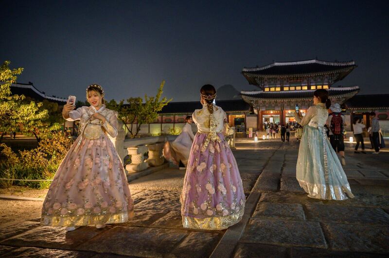 Visitors wearing traditional Korean hanbok dresses pose for photos during a night opening at Gyeongbokgung palace in central Seoul. AFP