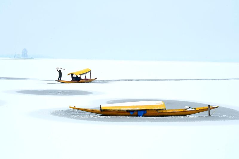 A boatman steers his boat at the partially frozen Dal Lake after a snowfall in Srinagar. AFP