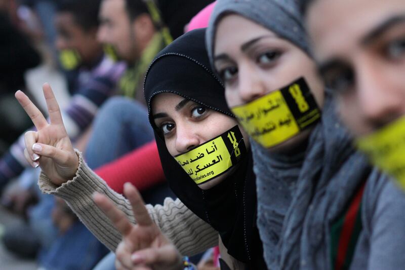 Egyptian activists stick their mothes with an Arabic slogan read " No for military trials for civilians" during a rally in Cairo's Tahrir square, Egypt, Friday, Nov.18, 2011. Tens of thousands of Egyptians rallied Friday in Cairo's Tahrir square with Islamists in the forefront to protest against what they say are attempts by the country's military rulers to designate themselves as the guardians of a new Egypt. It was one of the largest rallied in Egypt in recent months. (AP Photo/Amr Nabil) *** Local Caption ***  Mideast Egypt .JPEG-0af90.jpg
