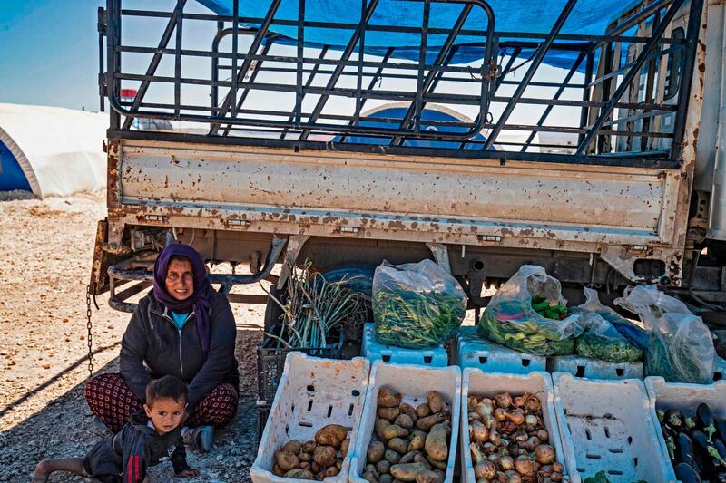 A displaced Syrian woman sits with her son next to her stall of vegetables at the Washukanni camp for the internally displaced in Syria's northeastern Hasakeh province, during Ramadan.   AFP
