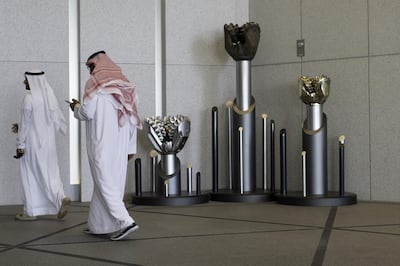 An employee checks his smartphone as he passes a display of drilling bits in the lobby of the Abu Dhabi National Oil Company (ADNOC) headquarters in Abu Dhabi, United Arab Emirates, on Thursday, Feb. 22, 2018. Adnoc is seeking to create world’s largest integrated refinery and petrochemical complex at Ruwais. Photographer: Christopher Pike/Bloomberg