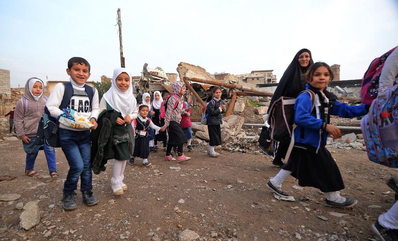 Iraqi students walk through a damaged road on their way back from school in the northern city of Mosul.  AFP