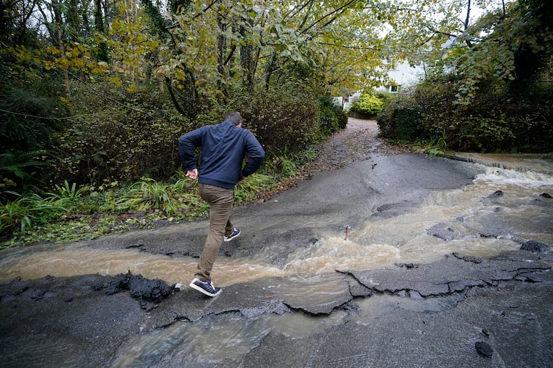 A man crosses a flood-damaged road in Faithlegg, Co. Waterford, Ireland. PA