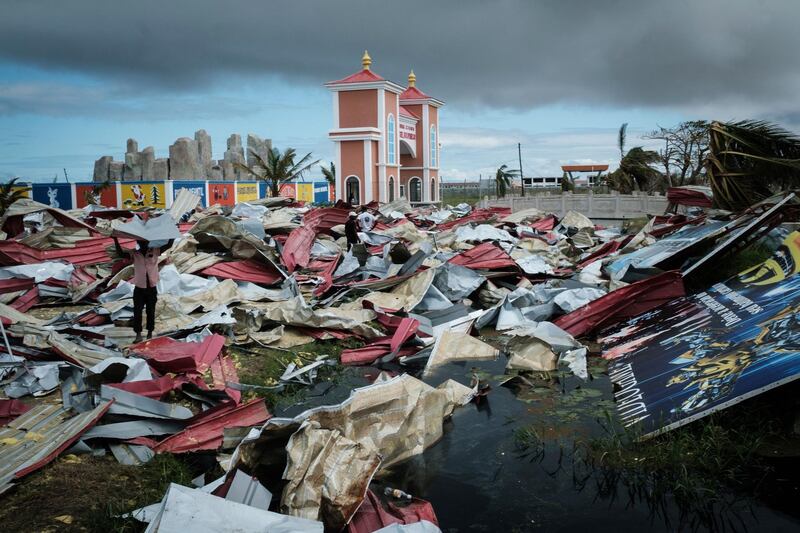 People collect metal sheets from a damaged supermarket to re-build their destroyed houses. AFP