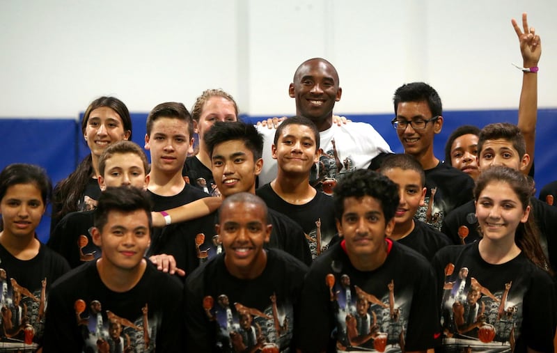 LA Lakers NBA player Kobe Bryant (C) poses for a family pictures after a training session at the Gems American Academy in Abu Dhabi on September, 26, 2013. Bryant arrived for a Health and Fitness Weekend, to promote awareness of diabetes in the United Arab Emirates in his first trip to a Middle East country.          AFP PHOTO/MARWAN NAAMANI (Photo by MARWAN NAAMANI / AFP)