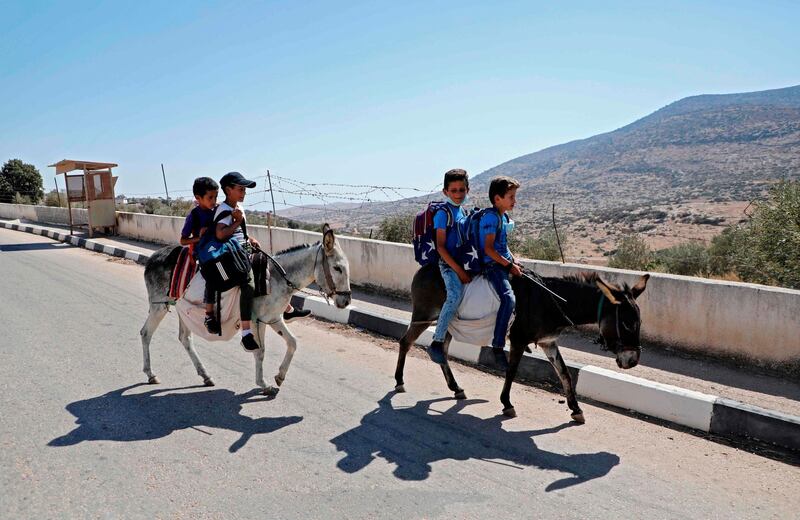 Palestinian students ride on a donkey in the village of Al-qaba in the Jordan  Valley as they head to school about five kilometres away from  their homes. AFP