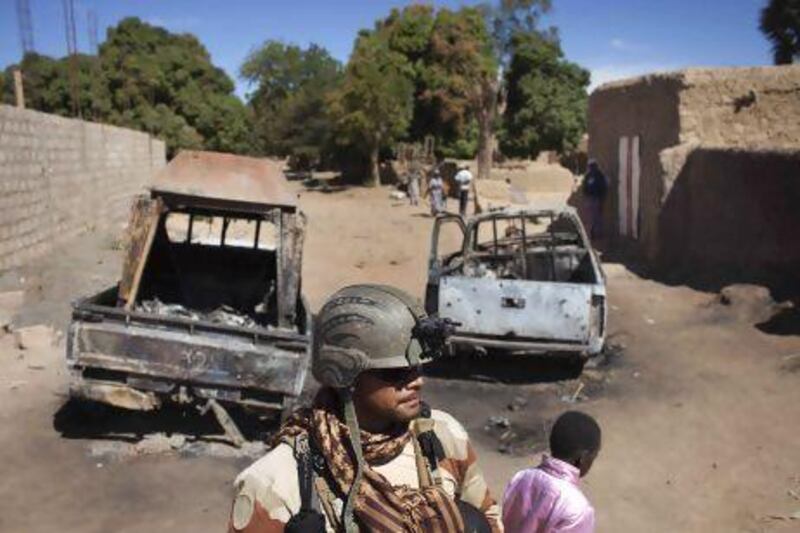 A French soldier stands guard in front of charred pickup trucks used by Islamist rebels in Diabaly.