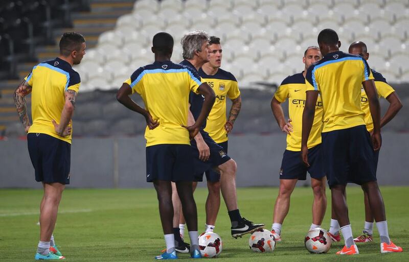 Manager Manuel Pellegrini talks with players during Manchester City's training session on Wednesday in Abu Dhabi at Al Jazira Club's Mohammed bin Zayed Stadium. Marwan Naamani / AFP / May 14, 2014