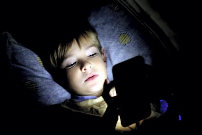 Boy using laptop on dark bedroom