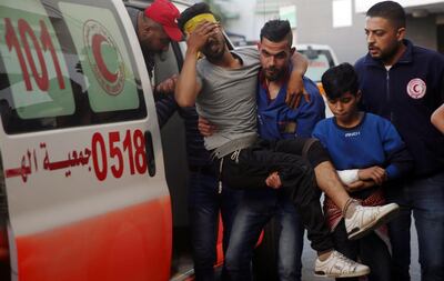 A medics worker helps a wounded youth, who was shot by Israeli troops during a protest at the Gaza Strip's border with Israel, into the treatment room of Shifa hospital in Gaza City, Friday, May 3, 2019. Three Palestinians, including two militants, were killed by Israeli fire Friday after gunshots from the Gaza Strip wounded two Israeli soldiers, officials said, in a new flare-up that shattered a month-long easing of hostilities that was mediated by Egypt. (AP Photo/Adel Hana)