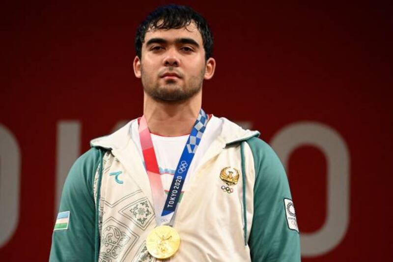 Gold medallist Uzbekistan's Akbar Djuraev stands on the podium for the victory ceremony of the men's 109kg weightlifting competition.
