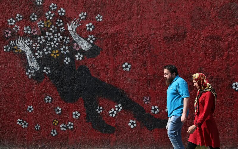 People walk past a mural in a sidewalk in downtown Tehran, Iran. AP Photo