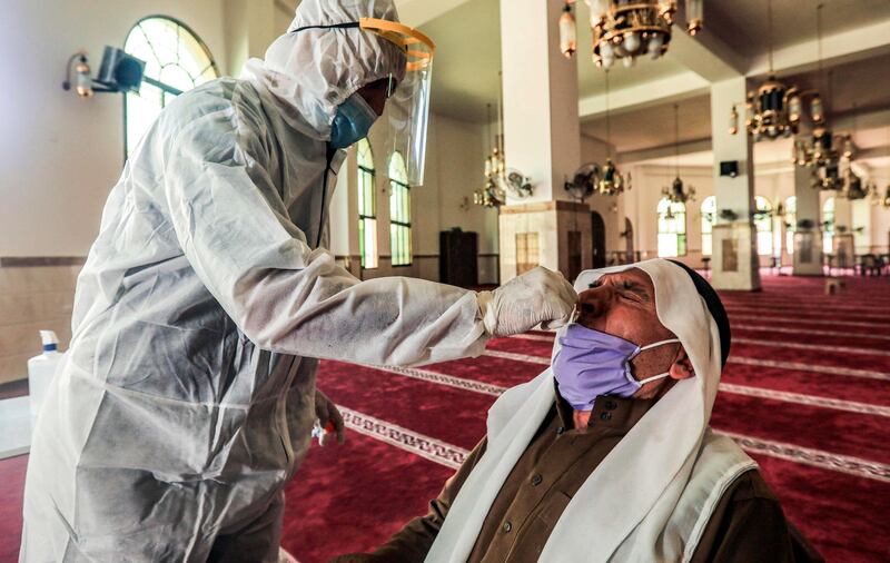 A Palestinian medical worker takes a swab sample from a man at a mosque in Gaza City on September 20, 2020, while testing for coronavirus disease cases. AFP