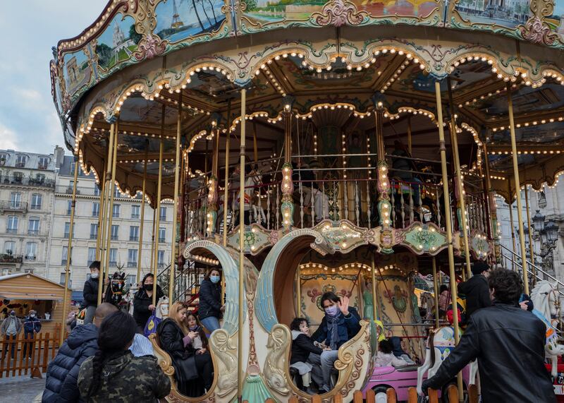People wearing masks sit on a carousel in Paris. One idea being considered is allowing only fully vaccinated people access to restaurants, cinemas and cultural venues. Photo: AP