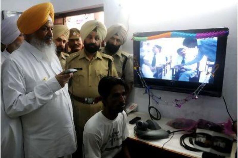 Hira Singh Gabbria, Punjab's jail minister, left, inspects equipment at the Central Jail in Amritsar as Jatinder Kumar, an inmate, talks with a judge through videoconferencing last year.