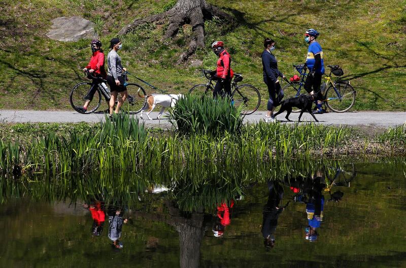 People wear face covering as they walk their dogs and ride bicycles in Central Park in New York, USA.  EPA