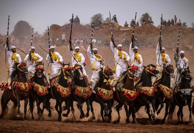 Moroccan horsemen raise their rifles during a traditional horse riding performance at a Moussem culture and heritage festival in the capital Rabat, on August 27, 2022.  (Photo by FADEL SENNA  /  AFP)