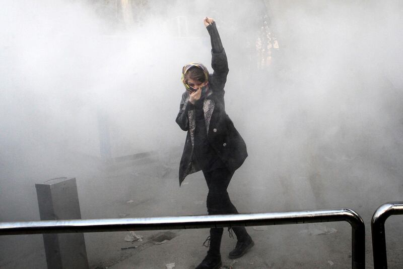 FILE - In this Dec. 30, 2017 photo made by an individual not employed by the Associated Press and obtained by the AP outside Iran, a university student attends a protest inside Tehran University while a smoke grenade is thrown by Iranian police, in Tehran, Iran. New unrest in Iran over the past 10 days appears to be waning, but anger over the economy persists. The protests in dozens of towns and cities also showed that a sector of the public was willing to openly call for the removal of Iranâ€™s system of rule by clerics -- frustrated not just by the economy but also by concern over Iranâ€™s foreign wars and general direction. (AP Photo, File)
