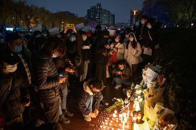 Demonstrators light candles for the victims of the Urumqi fire during a protest in Beijing on Sunday. Bloomberg