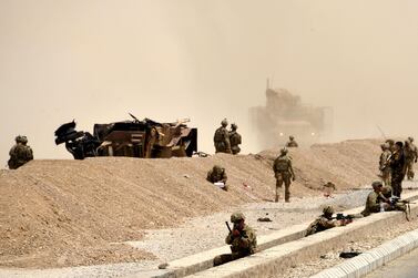US soldiers keep watch near the wreckage of their vehicle at the site of a Taliban suicide attack in Kandahar on August 2, 2017. Javed Tanveer / AFP