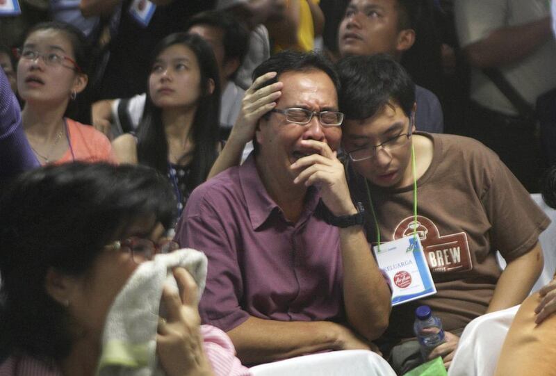 Relatives of passengers of the missing AirAsia flight react upon seeing the news on television about the findings of bodies near the site where the jetliner disappeared. This photo was taken at the crisis centre at Juanda International Airport in Surabaya, East Java, on December 30, 2014. Trisnadi/AP Photo