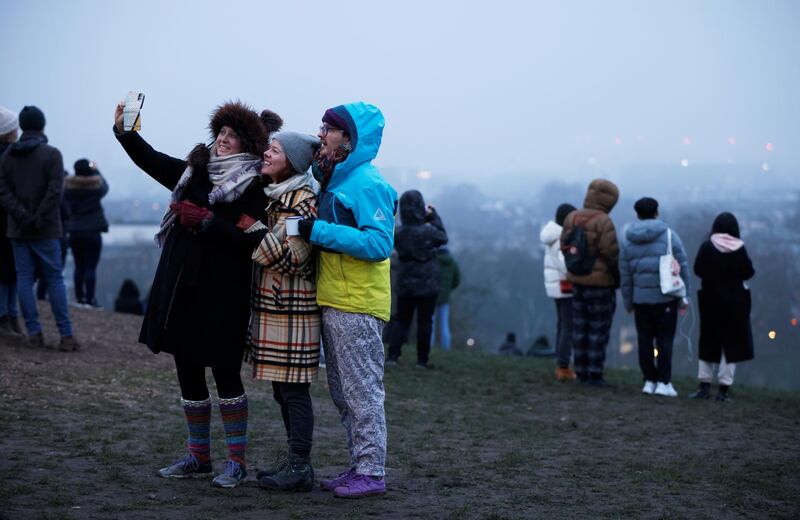 People take selfies at dawn on the first day of 2021 on Primrose Hill in London. Reuters