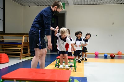 A PE teacher at Repton Abu Dhabi helps grade 1 pupils complete an obstacle challenge. Khushnum Bhandari / The National
