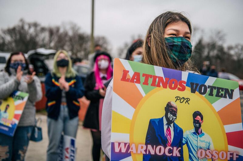 A woman holds a sign during a Latino meet and greet and literature distribution rally on December 30, 2020 in Marietta, Georgia. AFP