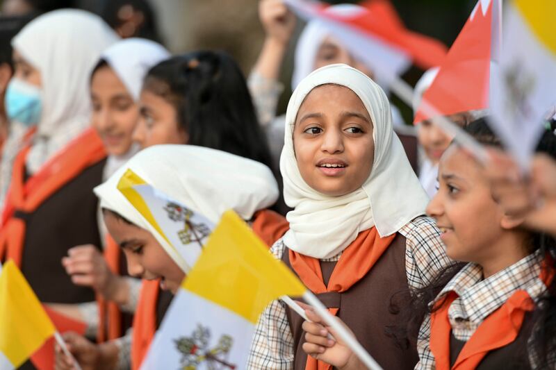 Schoolchildren wave flags to welcome the pontiff. Khushnum Bhandari / The National