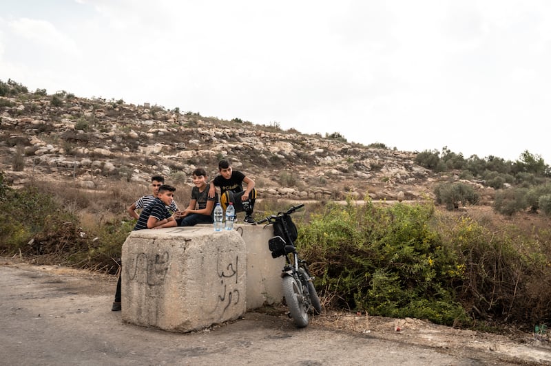 Young men and children hang around the seam zone to see if they will be allowed to help their family members, who have permits to access their farms in Qaffin, harvest their olives. Tanya Habjouqa / Noor for The National