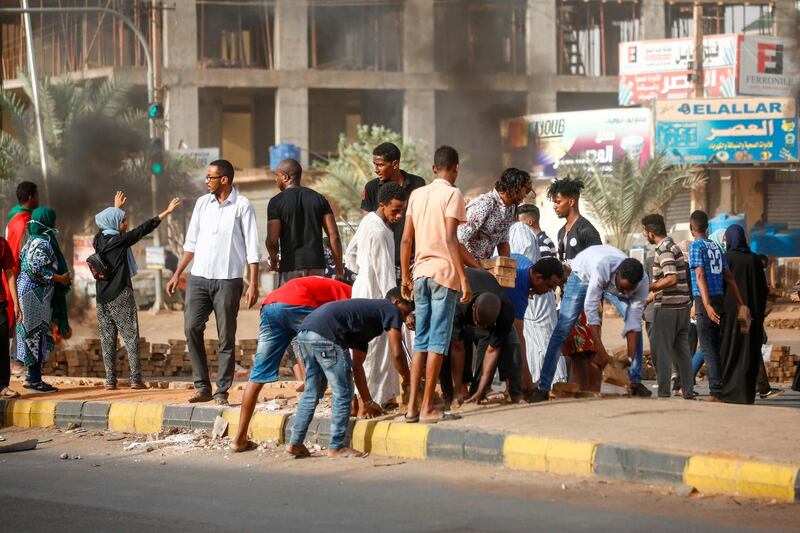 Sudanese protesters remove pavers to block the road as military forces tried to disperse the sit-in outside Khartoum's army headquarters. AFP