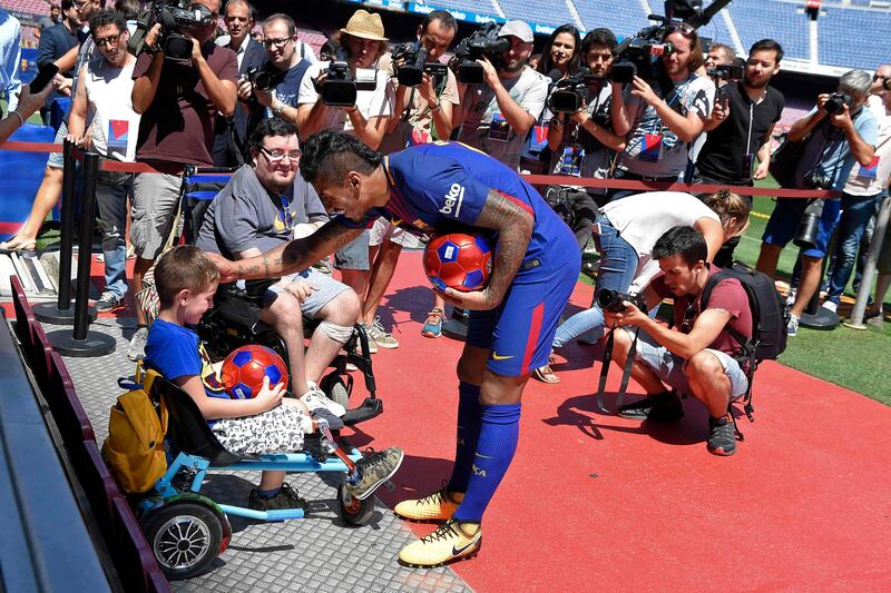 Barcelona's new Brazilian midfielder Paulinho gives a ball to a child in a wheelchair. Lluis Gene / AFP