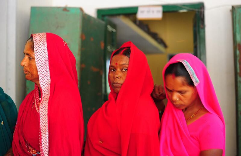 Indian women wait in a queue prior to casting their ballot at a polling station in Rae Bareli. Sanjay Kanojia / AFP