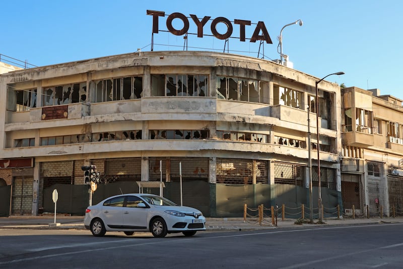 A car drives past a building in disrepair in Varosha.