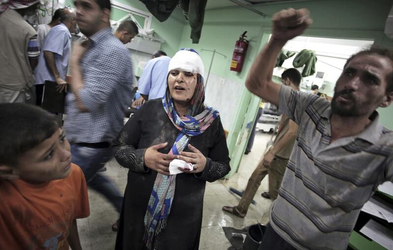 A Palestinian woman walks out of the emergency room after receiving treatment for injuries caused by an Israeli strike at a UN school in Jebaliya refugee camp, at the Kamal Adwan hospital in Beit Lahiya, northern Gaza Strip. Khalil Hamra / AP Photo