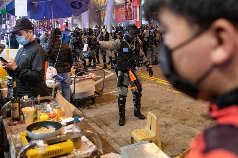 A riot police officers points a canister of pepper spray at a Lunar New Year temporary night market on Portland Street during a protest in the Mong Kok district of Hong Kong, China. Bloomberg