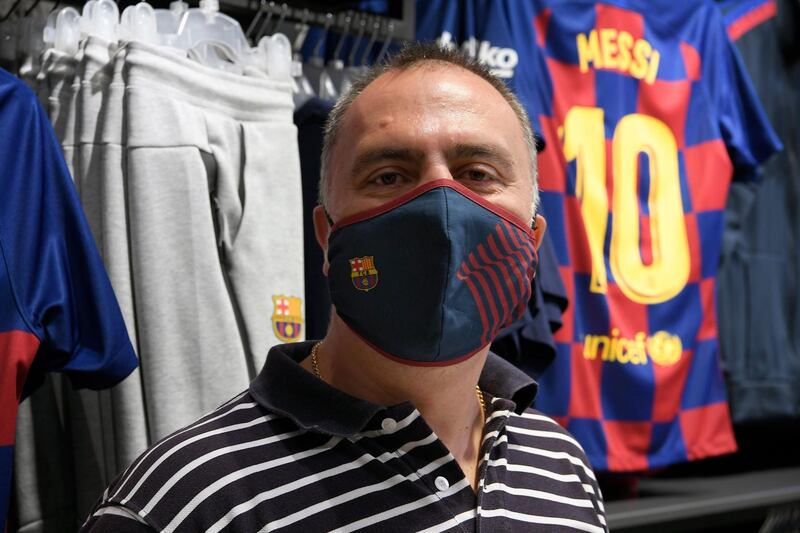 A supporter poses wearing a mask bearing the logo of FC Barcelona after buying it at the FC Barcelona store. AFP