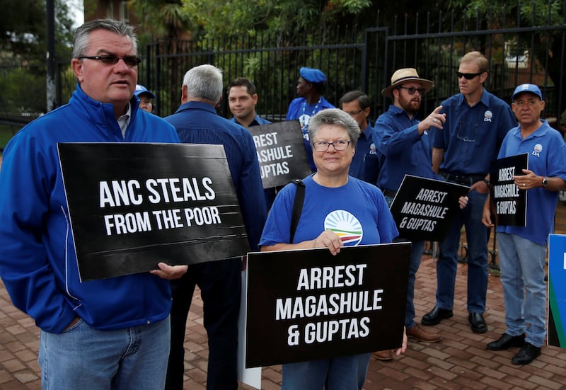 Protesters hold placards outside Bloemfontein Regional Court where people, who were arrested after armed police raided the luxury home of the Gupta family, were due to appear in February 2018. Reuters