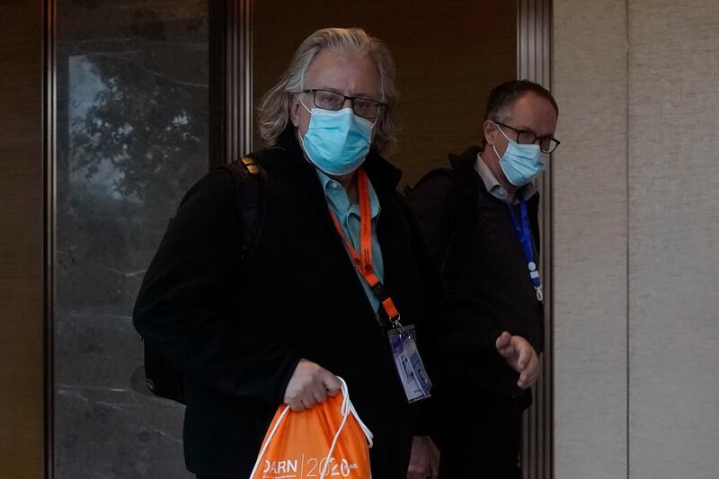 Members of the World Health Organisation team tasked with investigating the origins of Covid-19 walk down a corridor after meetings with the Chinese side in the cordoned wing of their hotel in Wuhan in central China's Hubei province. AP Photo