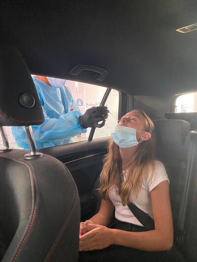 India Fuller Griffin, 14, receives a nasal swab at a drive-through testing centre in Abu Dhabi on Thursday. The National