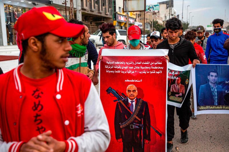 A protester holds up a banner depicting Iraqi Prime Minister Adel Abdel Mahdi as a sniper with a caption above in Arabic reading "we demand the fair and honest judiciary and the international courts to try and hold accountable Adel Abdel Mahdi and his mercenary forces for unjustly  killing almost 700 innocent Iraqis", during an anti-government demonstration, also calling for freedom of the press, in the southern Iraqi city of Basra.  AFP