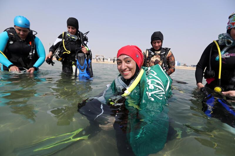 Abrar Abu Abdullah, a Saudi female diver smiles as she wears Saudi national flag over her shoulders as she enters the sea to dive at Half Moon Beach open-water dive site in Dhahran, Saudi Arabia, September 15, 2018. Picture taken September 15, 2018. REUTERS/Hamad I Mohammed