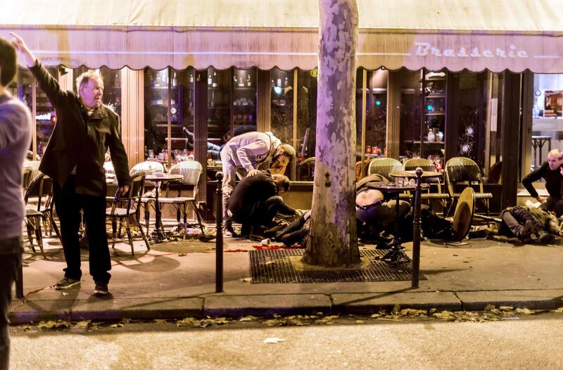 (FILES) In this file photo taken on November 13, 2015 people lie on the pavement at the terrasse of the Cafe Bonne Biere in Paris, following a series of coordinated attacks in and around Paris.  French National Antiterrorist Prosecution announced on November 29, 2019 that it required an Assize trial, for Salah Abdeslam and 19 other persons suspected of being involved in the Paris attacks that killed 130 people on a single day in Paris four years ago. The trial is set in 2021 in Paris.  / AFP / Anthony DORFMANN
