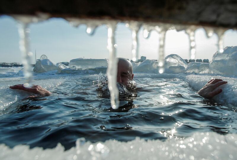 An enthusiast of winter swimming takes a dip in icy water, with buildings of Chinese border city Heihe seen in the background across the frozen Amur River in Blagoveshchensk, Russia. Reuters