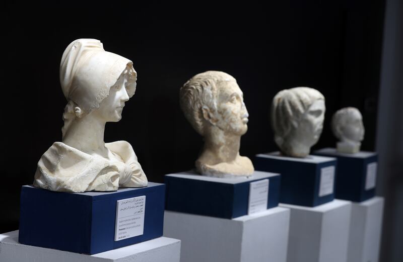 A white marble bust representing a young woman from the colonial era, left, is displayed at the exhibition.